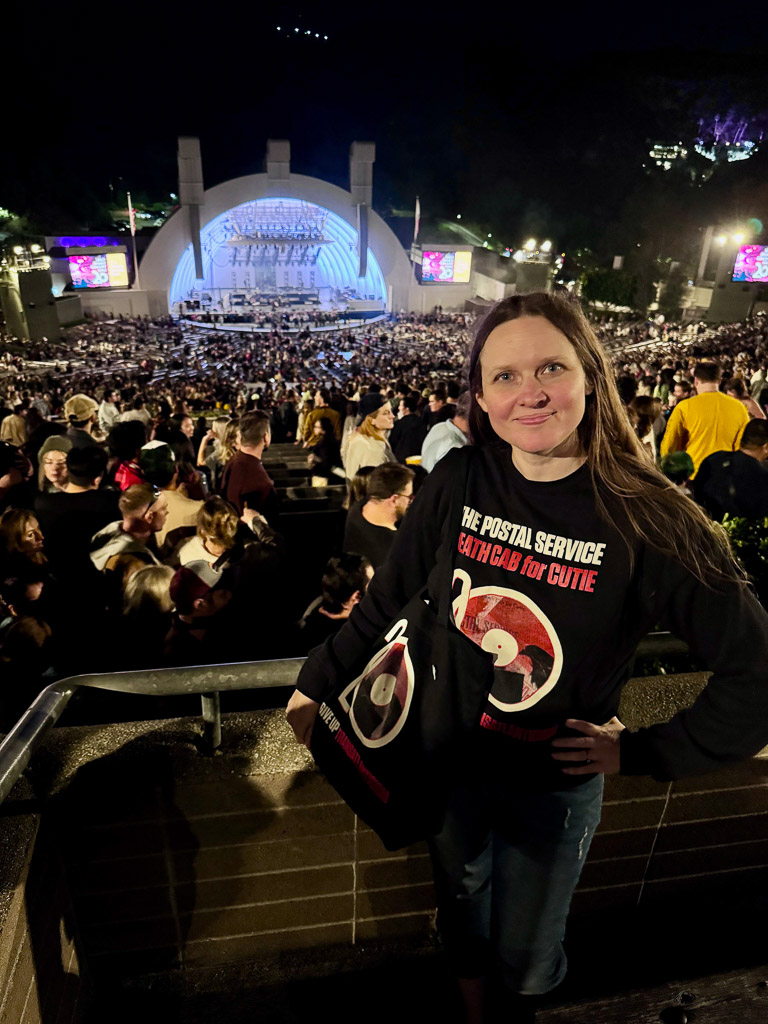 Me, Shannon, standing with the Hollywood Bowl in the background. I'm wearing a concert sweatshirt and holding a matching concert tote bag.